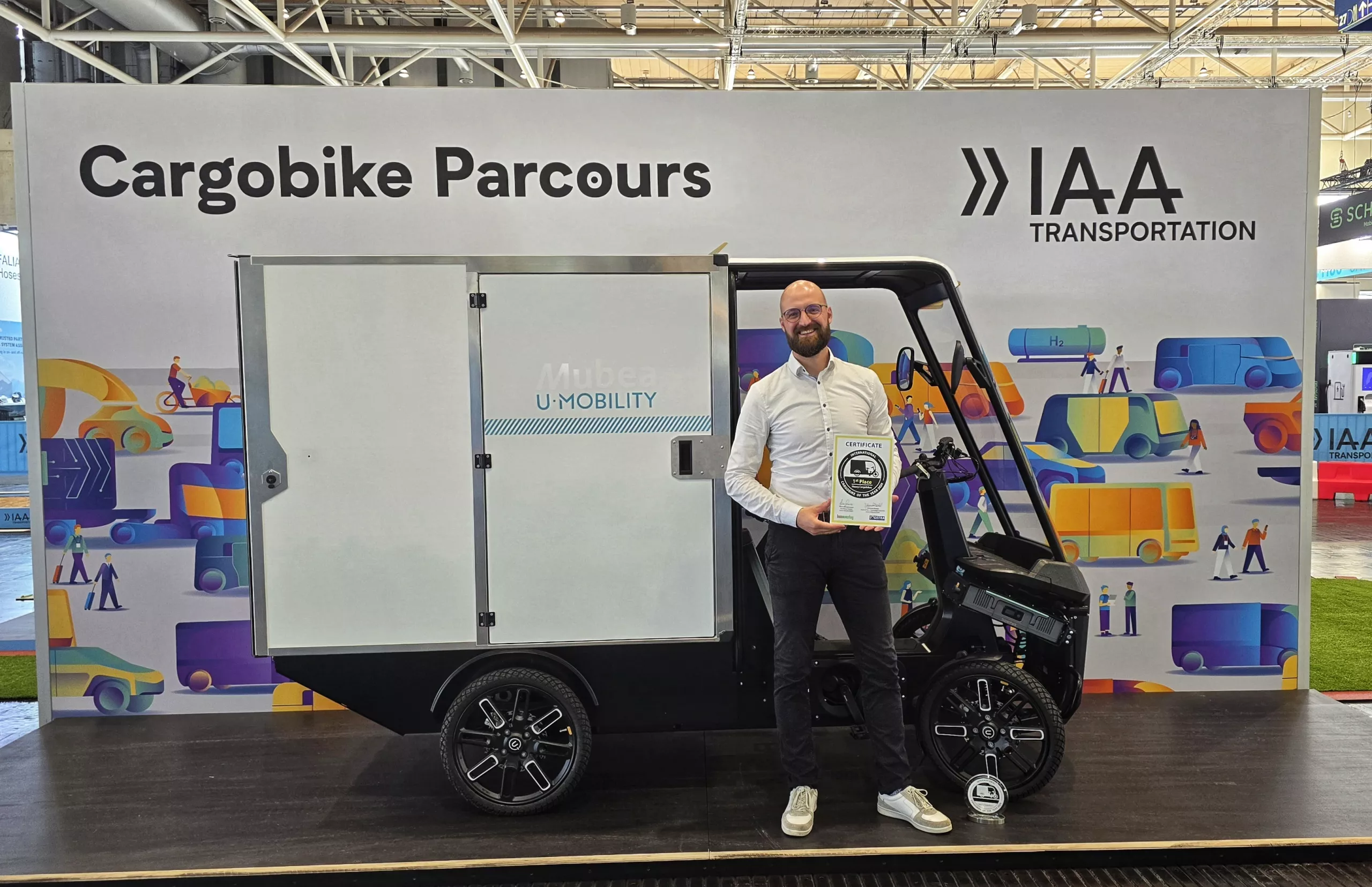 IAA: Mubea employee holding the "Cargo Bike of the Year" award in front of the Cargo PACK