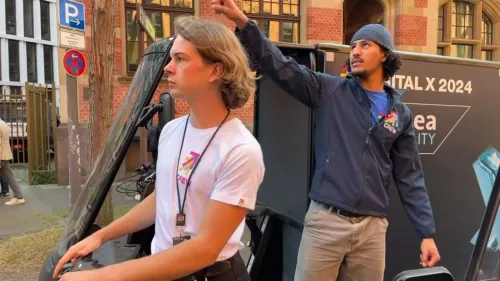 Zwei Mitarbeiter aus der Crew sind im Rahmen der Digital X 2024 mit einem E-Scooter und einem Lastenrad zu sehen