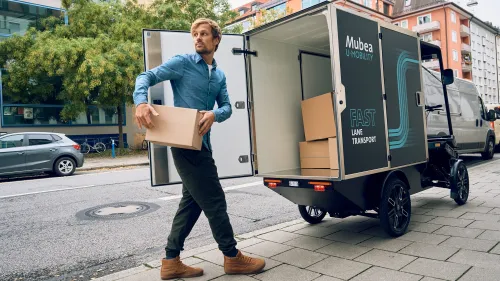Junger Paketbote lädt Pakete in den PACK.